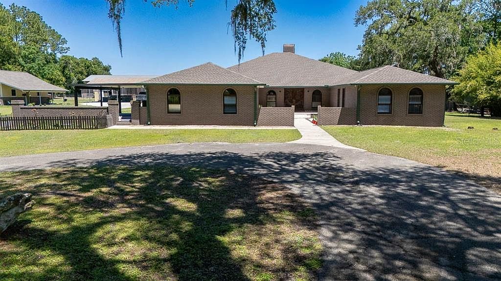 Front elevation of the brick ranch home with arched windows and mature oak canopy