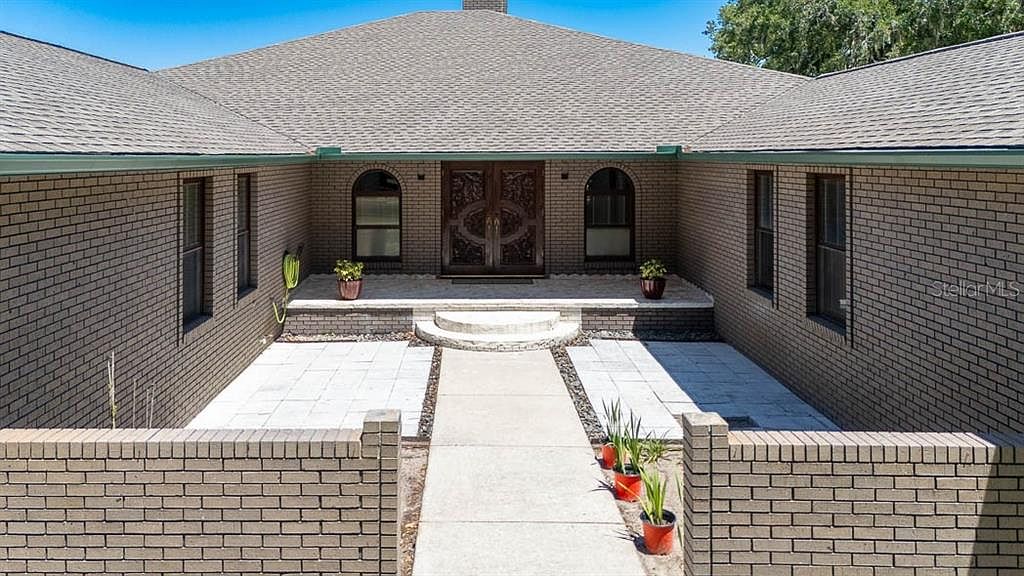 Brick entry courtyard with carved double doors and ornamental planters