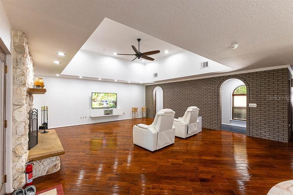 Great room with stone fireplace, wood floors, and recessed tray ceiling